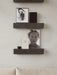 Two dark marble Plinth Shelves mounted on a light grey wall, styled with books, art, and a small decorative bowl.
