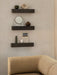 Three dark marble Plinth Shelves, styled with a Pepe Marble Mirror and decor, above the corner of a yellow Eave Sofa.