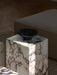 The black Échasse Bowl from Audo CPH sits on a Calacatta Viola marble Plinth, casting a shadow in a sunlit living room.