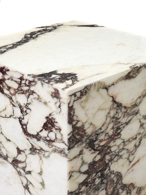 A detailed close-up of the corner of the Plinth Rose Tall, showcasing its polished white marble with rich, deep red veining.