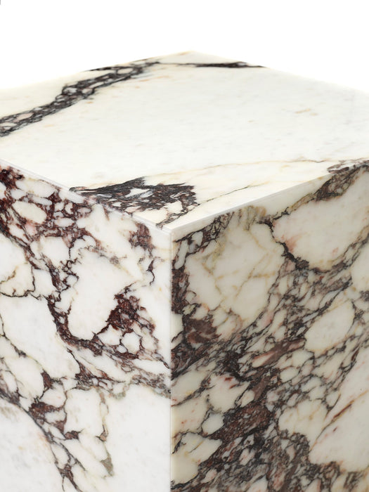 A detailed close-up of the corner of the Plinth Rose Tall, showcasing its polished white marble with rich, deep red veining.
