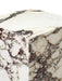 A detailed close-up of the corner of the Plinth Rose Tall, showcasing its polished white marble with rich, deep red veining.