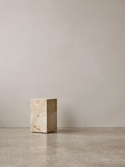 The Plinth Tall in Kunis Breccia marble stands on a polished terrazzo floor in a minimalist room against a neutral wall.