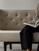 A person reads a magazine on the Radiohus Sofa P2, showing a close-up of the beige quilted backrest with brown buttons.