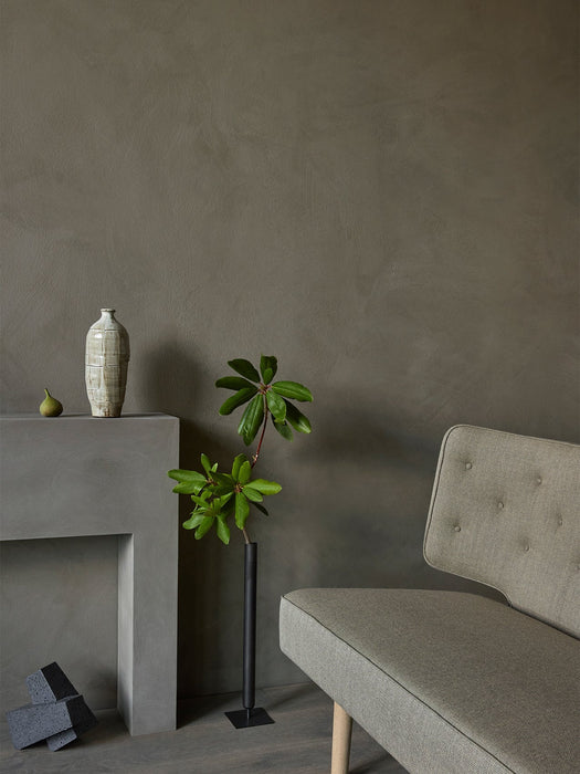 A detailed shot of the Radiohus Sofa in a textured grey fabric, set in a minimalist room with a concrete plinth and decor.