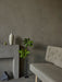 A detailed shot of the Radiohus Sofa in a textured grey fabric, set in a minimalist room with a concrete plinth and decor.