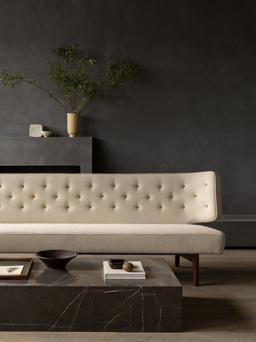 A cream-coloured, button-tufted Radiohus Sofa sits against a dark grey wall, with a black marble Plinth Grand coffee table.