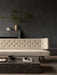 A cream-coloured, button-tufted Radiohus Sofa sits against a dark grey wall, with a black marble Plinth Grand coffee table.