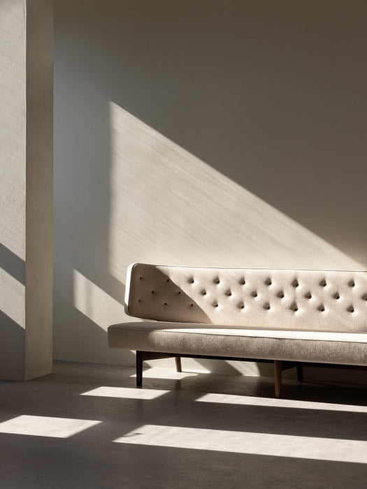 The Radiohus Sofa P3 in cream tufted upholstery, sitting in a room with dramatic sunlight casting shadows across the wall.