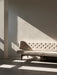 The Radiohus Sofa P3 in cream tufted upholstery, sitting in a room with dramatic sunlight casting shadows across the wall.