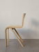 A side-profile of the Ready Dining Chair in natural oak veneer against a white wall, highlighting its cantilevered design.