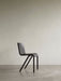 Side view of the black Ready Dining Chair, showcasing its cantilevered silhouette in a minimalist room with a neutral wall.