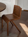 A dark oak Ready Dining Chair with a cantilevered design sits on a stone tile floor next to a matching table.