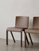 Two Ready Dining Chairs in dark oak veneer, standing side by side in a minimalist space against a light-coloured wall.