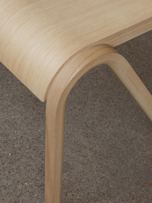 A close-up of the Ready Dining Chair in natural oak, highlighting the curved joint where the leg meets the form-pressed seat.