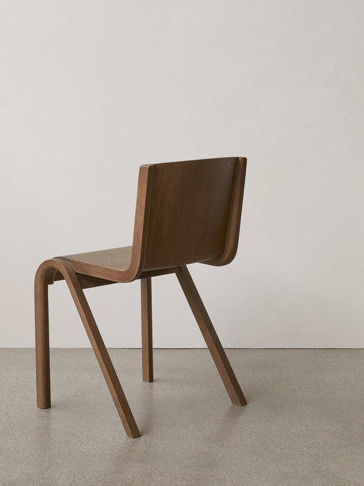 The Ready Dining Chair in red stained oak, seen from a three-quarter back view, highlighting its cantilevered design.