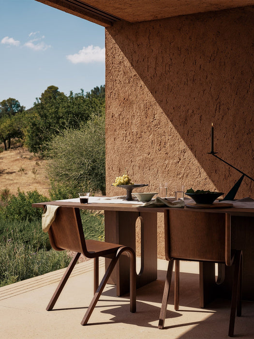 Two Ready Dining Chairs at a wooden Androgyne Dining Table on a sunny terrace with an Interconnect Candle Holder and food