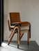 A stack of three upholstered Ready Dining Chairs in different finishes: dark wood and tan leather, and oak with beige fabric.
