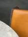 A close-up of the Ready Dining Chair with tan upholstery and dark wood frame beside a marble Harbour Column Dining Table.