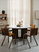 Four Ready Dining Chairs in dark wood with upholstered seats surround a round, dark wood Androgyne Dining Table.