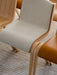 Close-up of the Ready Dining Chair, Front Upholstered, showing its light oak frame and textured beige fabric on a ribbed rug.