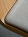 Close-up of the Ready Dining Chair's seat corner, showing textured beige woven upholstery and curved light oak frame.