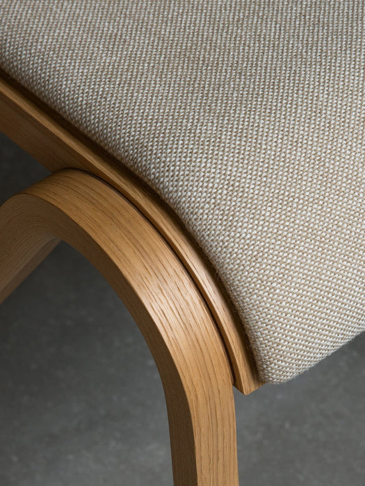 Close-up of the Ready Dining Chair's seat, showing the beige woven upholstery and the grain of the curved oak frame.