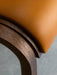A detail shot of the Ready Dining Chair highlighting the smooth, tan upholstered seat against the textured, dark oak frame.