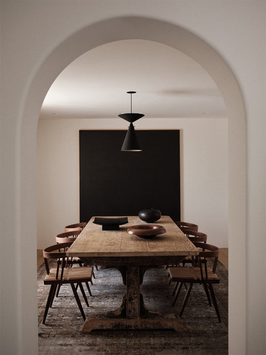 A rustic wooden dining table styled with the Rond Bowl, Releve Platter, and Surround Vase, viewed through a white archway.