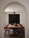 A rustic wooden dining table styled with the Rond Bowl, Releve Platter, and Surround Vase, viewed through a white archway.