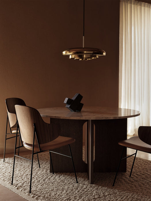 A dining room with a brass Resonant Pendant light over an Androgyne Dining Table, Penguin Chairs and Converge Book Ends.