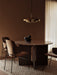 A dining room with a brass Resonant Pendant light over an Androgyne Dining Table, Penguin Chairs and Converge Book Ends.