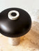 A close-up view of the Reverse Table Lamp, showing its travertine stone base and dimmer switch atop the bronzed shade.