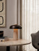 A lit Reverse Table Lamp on a Harbour Column Lounge Table next to a Harbour Lounge Chair in a calm, modern interior.
