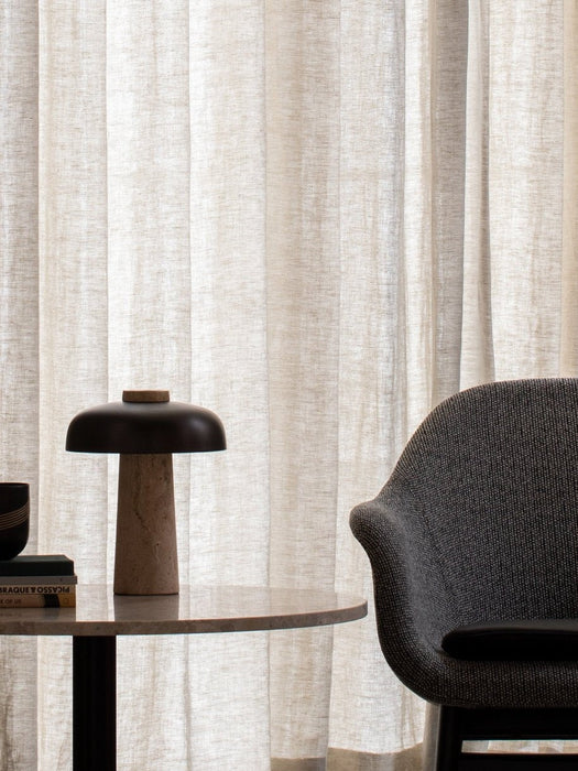 A close-up of the Reverse Table Lamp on a Harbour Column Lounge Table next to the arm of a grey Harbour Lounge Chair.
