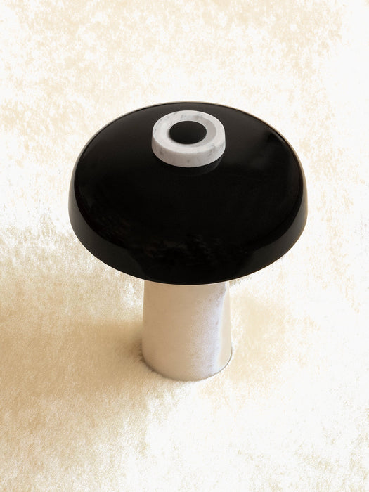 A high-angle view of the Reverse Table Lamp, with a glossy black shade, white marble base, and marble dimmer switch.