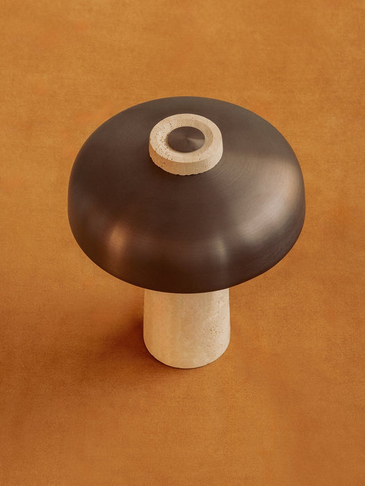 Top-down view of the Reverse Table Lamp, highlighting its bronzed shade, travertine base, and dimmer on an ochre surface.