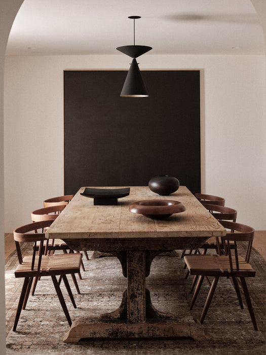 A rustic wooden dining table in a warmly lit room, featuring the Audo Releve Platter, Surround Vase, and Rond Bowl.