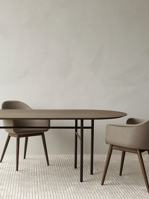 Snaregade Oval Table, shown in a dark wood finish, accompanied by two Harbour Dining Chairs on a light-coloured Houkime Rug.