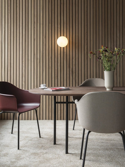 A dining room featuring the Snaregade Oval Table, Harbour chairs, and a Cyclades vase against a wood-slat wall.