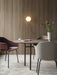 A dining room featuring the Snaregade Oval Table, Harbour chairs, and a Cyclades vase against a wood-slat wall.