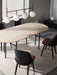 Audo's Snaregade Oval Table in oak with black legs, surrounded by black chairs. A TR Bulb Suspension Frame hangs above.