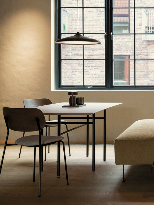 The rectangular Snaregade Dining Table sits in a warmly lit room with two chairs, a pendant lamp, and a large window.