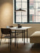 The rectangular Snaregade Dining Table sits in a warmly lit room with two chairs, a pendant lamp, and a large window.