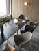A black Snaregade Dining Table with Harbour Chairs in a modern room with a slatted wooden wall and a TR Bulb on the table.
