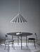 The black, round Snaregade Dining Table in a grey room with two chairs. A large, grey, pleated pendant lamp hangs above.