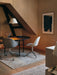 A warmly lit room with a round Snaregade Dining Table, Harbour Dining Chairs, and a white Levitate Pendant lamp.