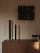 A lifestyle image of two black Stance Vases and a Relevé Platter on a wooden sideboard, with dark textured art on the wall.