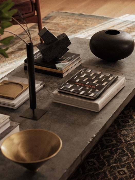 Lifestyle image of a coffee table with Audo's Stance Vase, Converge Book Ends, Surround Vase, and Taper Bowl.