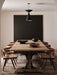 A dining room with a rustic wooden table set with the Rond Bowl, Surround Vase, and Relevé Platter under a pendant light.